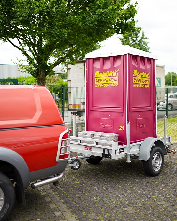 Die mobile Toilette wird mit einem Auto weggefahren.